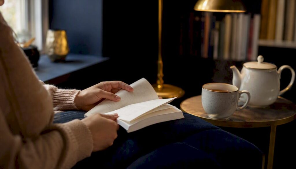 Hands holding a memoir book in cozy reading nook